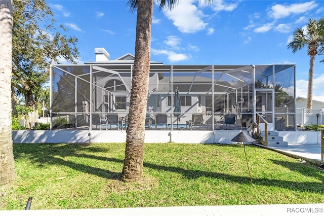 back of property featuring a lanai and a lawn