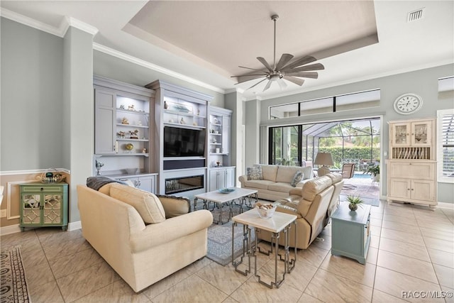 living area featuring a raised ceiling, visible vents, ornamental molding, and ceiling fan