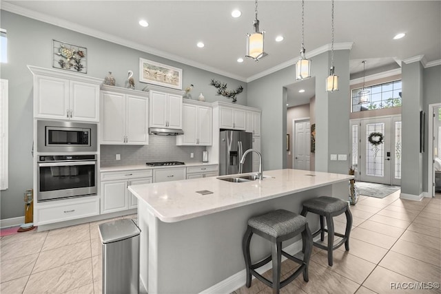 kitchen with appliances with stainless steel finishes, crown molding, white cabinets, decorative backsplash, and a sink