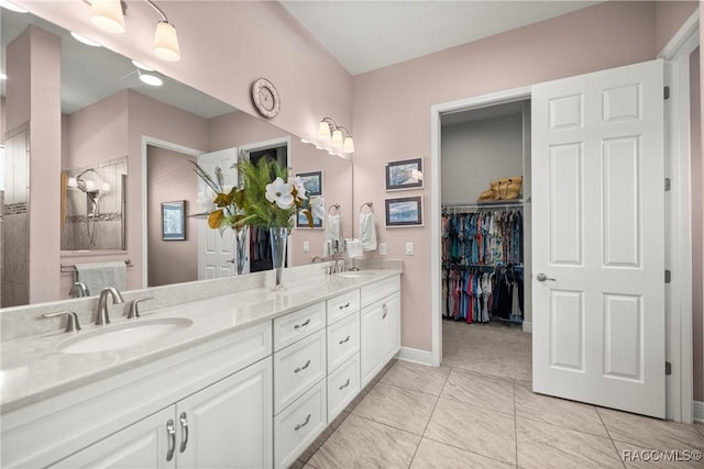 bathroom featuring a spacious closet, double vanity, and a sink