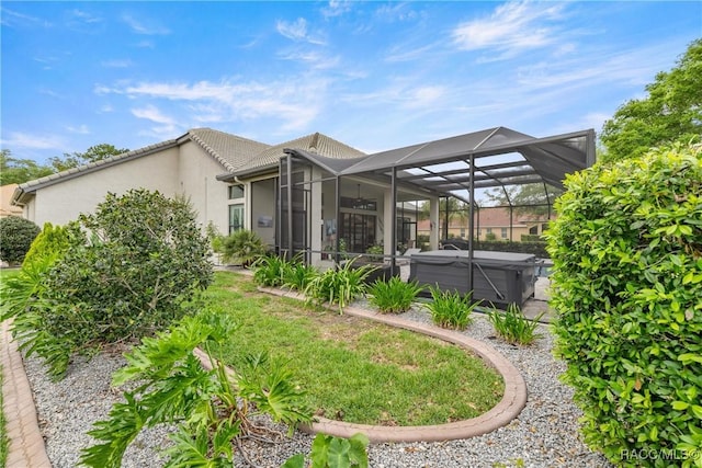 back of property with stucco siding, a tiled roof, a lanai, and a hot tub