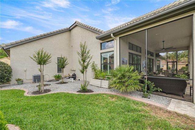 exterior space featuring a yard, ceiling fan, stucco siding, and a tile roof