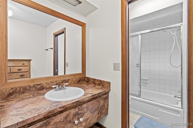 bathroom featuring combined bath / shower with glass door, a textured ceiling, and sink