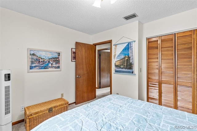 carpeted bedroom with a textured ceiling and a closet