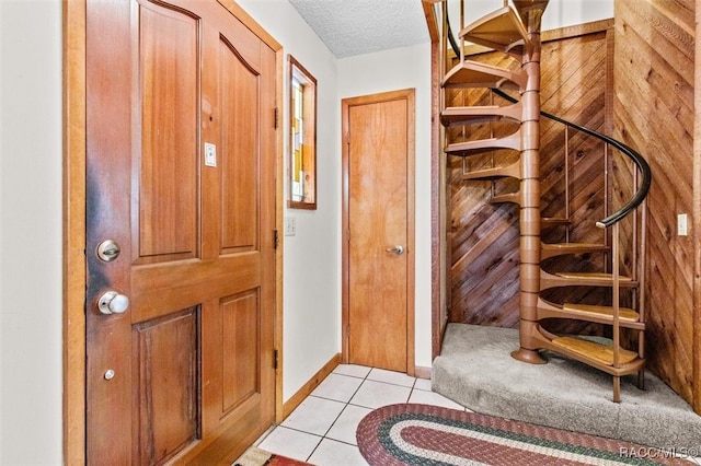 foyer with wood walls, light tile patterned floors, and a textured ceiling