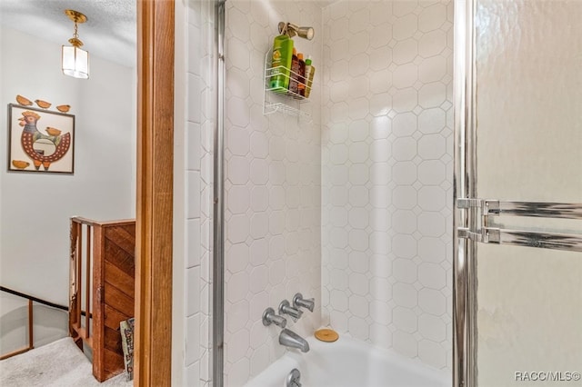 bathroom with a textured ceiling and  shower combination