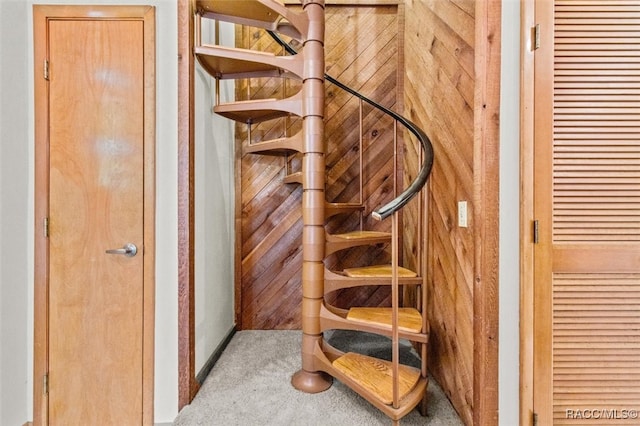 stairway with carpet and wood walls