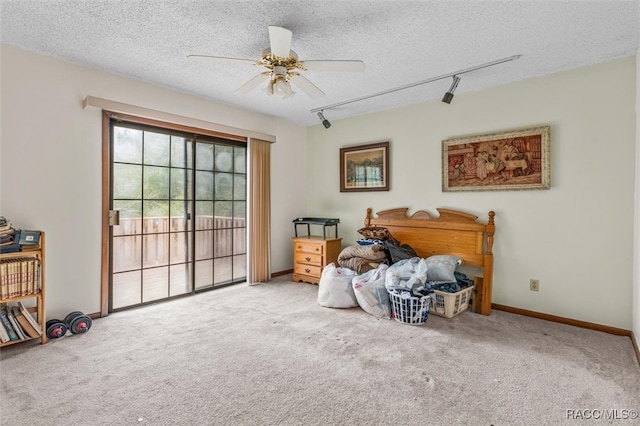 misc room featuring rail lighting, ceiling fan, carpet floors, and a textured ceiling