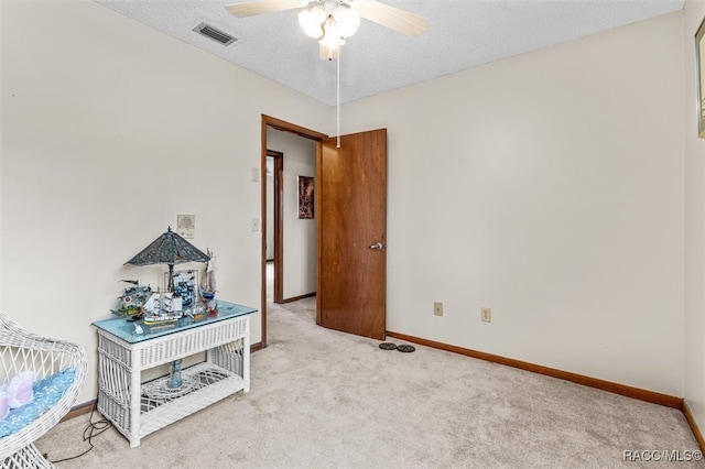 bedroom featuring light carpet, ceiling fan, and a textured ceiling