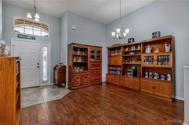 entryway featuring a towering ceiling, dark wood-type flooring, and a notable chandelier