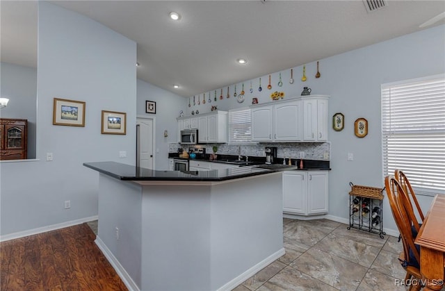 kitchen with appliances with stainless steel finishes, backsplash, sink, white cabinets, and lofted ceiling