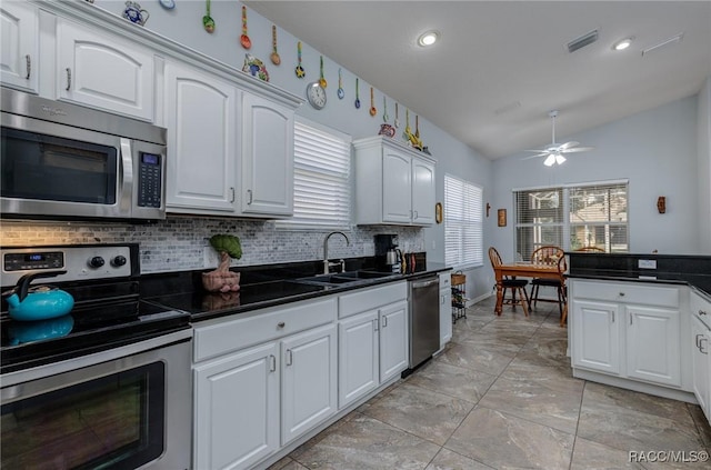 kitchen featuring stainless steel appliances, vaulted ceiling, ceiling fan, sink, and white cabinets