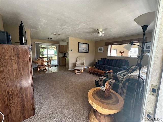 living room featuring carpet flooring, a textured ceiling, and ceiling fan