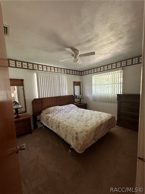 carpeted bedroom with ceiling fan and a textured ceiling