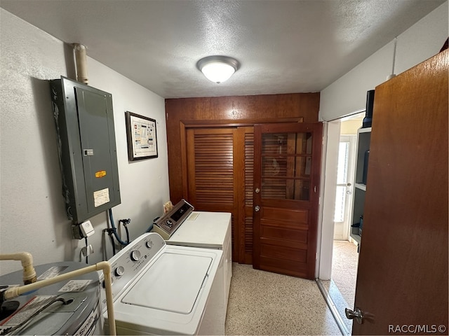 washroom featuring a textured ceiling, electric panel, and washing machine and clothes dryer