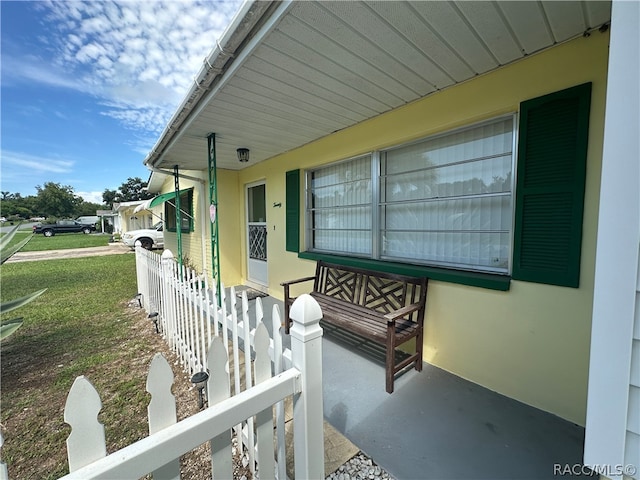 view of exterior entry with a lawn and a porch