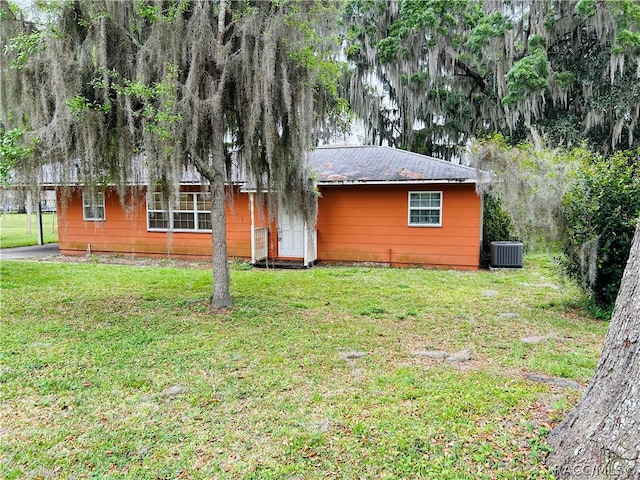 ranch-style house with central air condition unit and a front lawn