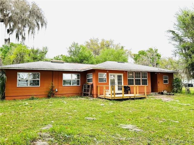 back of house featuring a lawn, a deck, and french doors