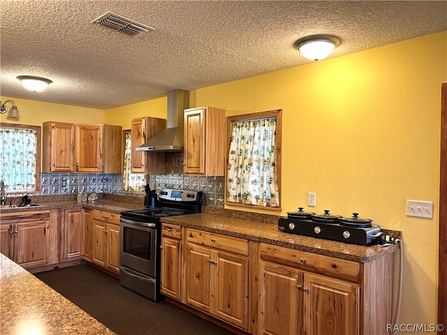 kitchen featuring stainless steel electric stove, wall chimney exhaust hood, plenty of natural light, and backsplash