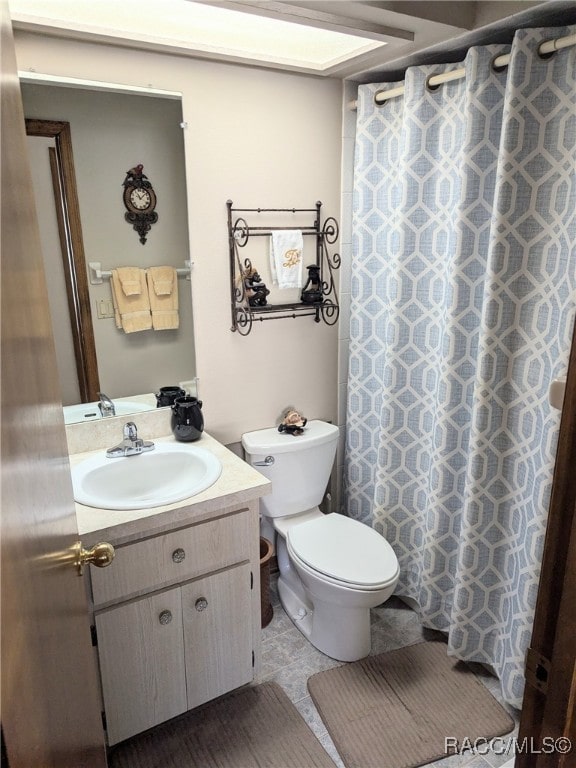 bathroom featuring a shower with shower curtain, tile patterned floors, vanity, and toilet