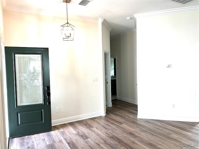 foyer with crown molding, hardwood / wood-style floors, and a chandelier