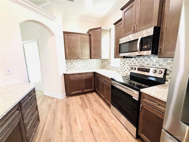 kitchen featuring light stone counters, appliances with stainless steel finishes, light hardwood / wood-style floors, and backsplash