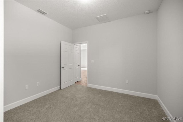 spare room with a textured ceiling and carpet