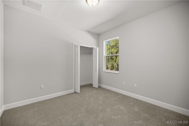 unfurnished bedroom with carpet, a closet, and a textured ceiling