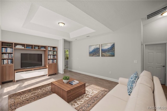 living room with wood-type flooring and a tray ceiling