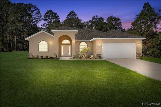 view of front of property with a garage and a yard