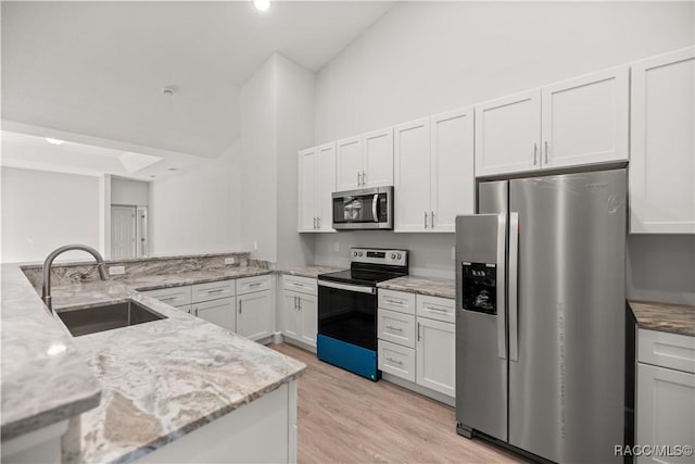 kitchen featuring kitchen peninsula, sink, white cabinetry, stainless steel appliances, and light stone counters