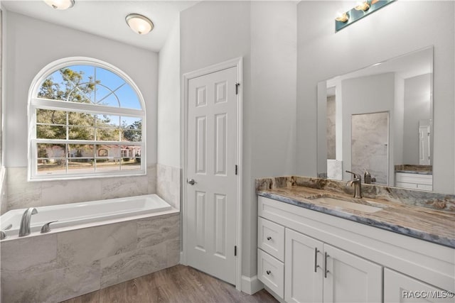 bathroom featuring tiled bath, hardwood / wood-style floors, and vanity