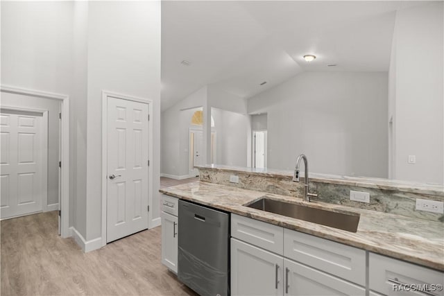 kitchen with light stone countertops, white cabinets, dishwasher, sink, and vaulted ceiling