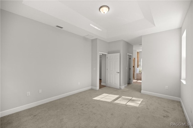 unfurnished bedroom with light carpet and a raised ceiling