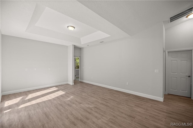 spare room featuring hardwood / wood-style flooring and a raised ceiling