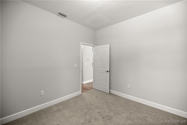 spare room featuring a textured ceiling and carpet