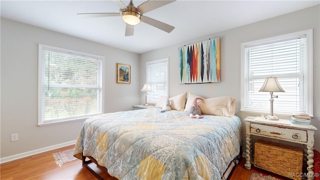 bedroom with multiple windows, hardwood / wood-style flooring, and ceiling fan