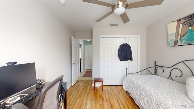 bedroom with light wood-type flooring, ceiling fan, and a closet