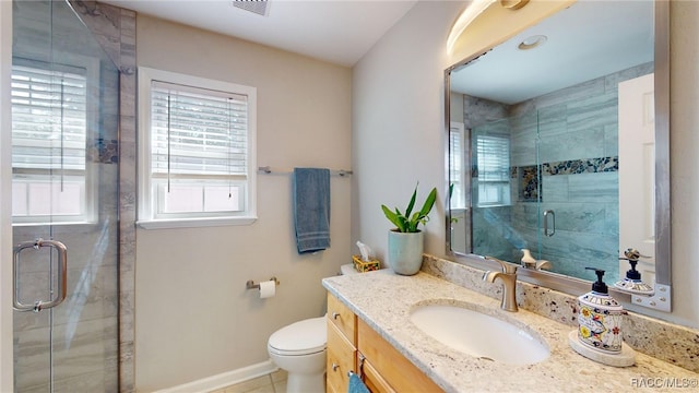 bathroom with a shower with door, vanity, tile patterned floors, and toilet