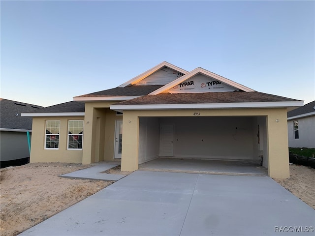 single story home with a shingled roof, concrete driveway, an attached garage, and stucco siding