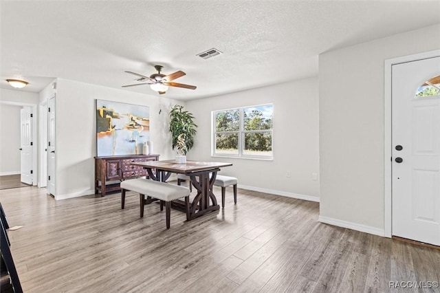 dining area with ceiling fan, light hardwood / wood-style flooring, and a textured ceiling