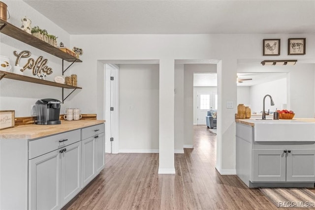 bar with sink, gray cabinets, light hardwood / wood-style floors, and a textured ceiling