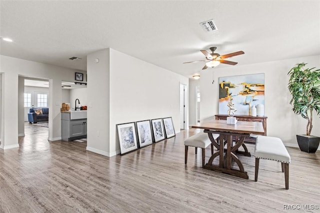 dining area with sink, light hardwood / wood-style floors, and ceiling fan