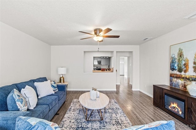 living room with wood-type flooring, ceiling fan, and a textured ceiling