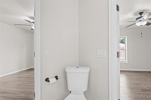 bathroom with wood-type flooring, a textured ceiling, ceiling fan, and toilet