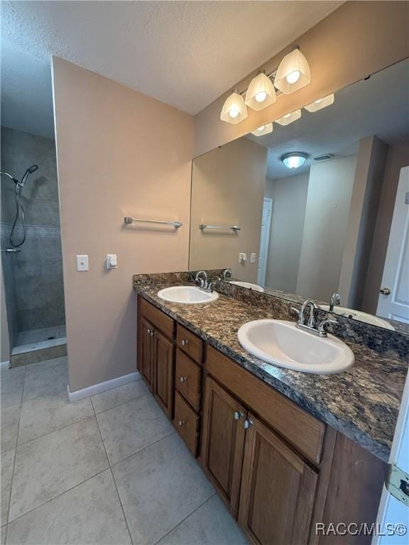 bathroom with vanity, tiled shower, and tile patterned floors