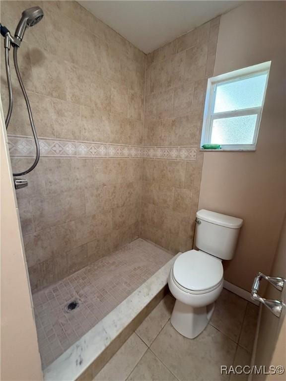 bathroom with a tile shower, tile patterned flooring, and toilet