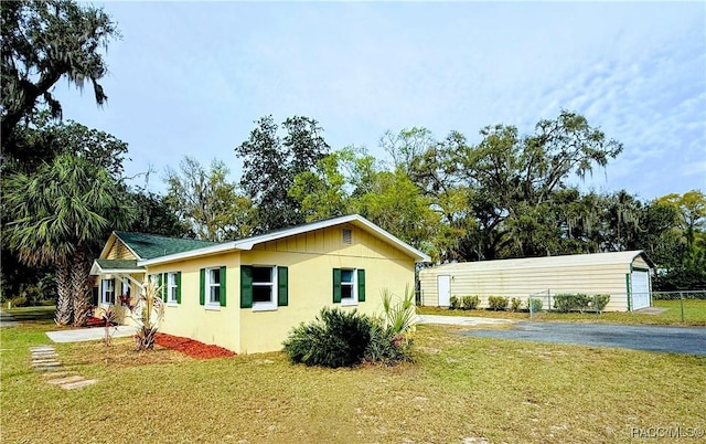 view of property exterior with a garage, an outbuilding, and a lawn