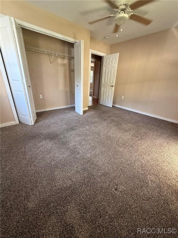 unfurnished bedroom with carpet, a closet, and ceiling fan