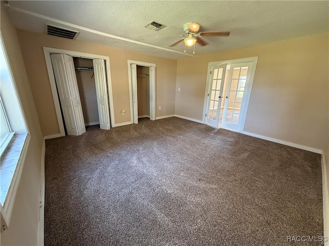 unfurnished bedroom featuring french doors, two closets, carpet floors, ceiling fan, and a textured ceiling